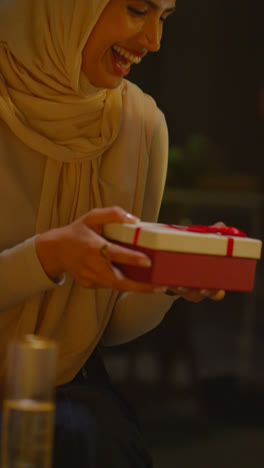 Vertical-Video-Of-Woman-Giving-Female-Friend-Birthday-Present-At-Home-With-Party-Balloons-In-Background-1